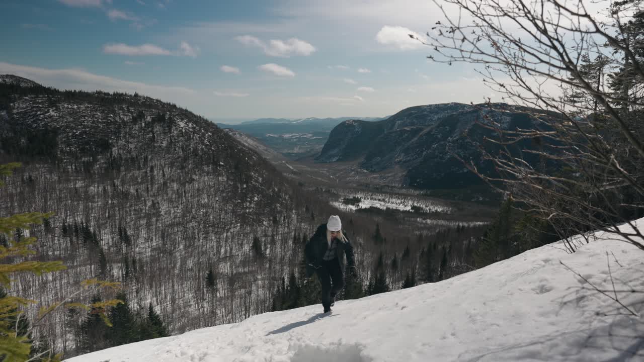 chica caucásica escalando una empinada y nevada ladera de montaña en mont du dome canadá - plano general