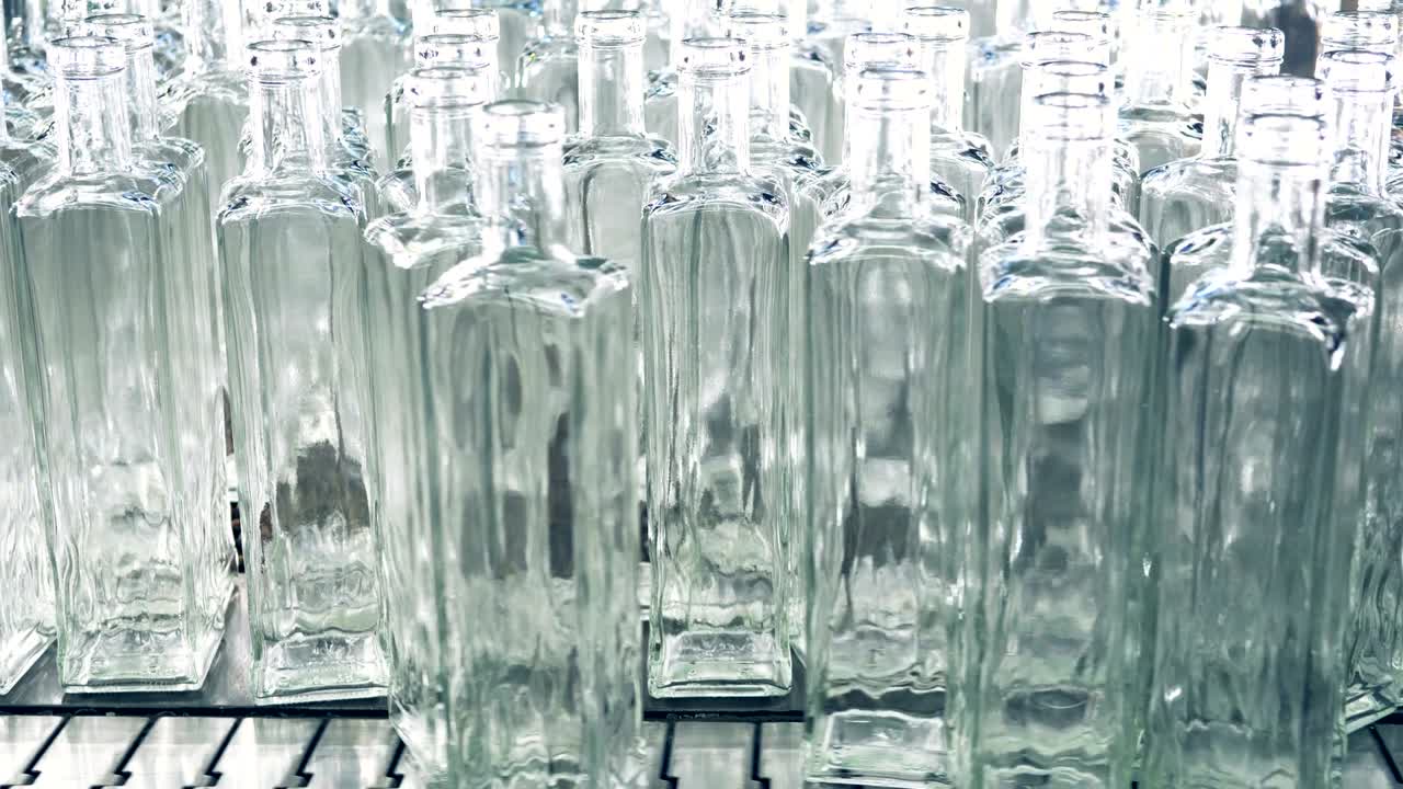 una pila de botellas transparentes recién hechas siendo empujadas a la cinta transportadora