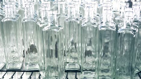 a pile of transparent newly-made bottles being pushed onto the conveyor belt