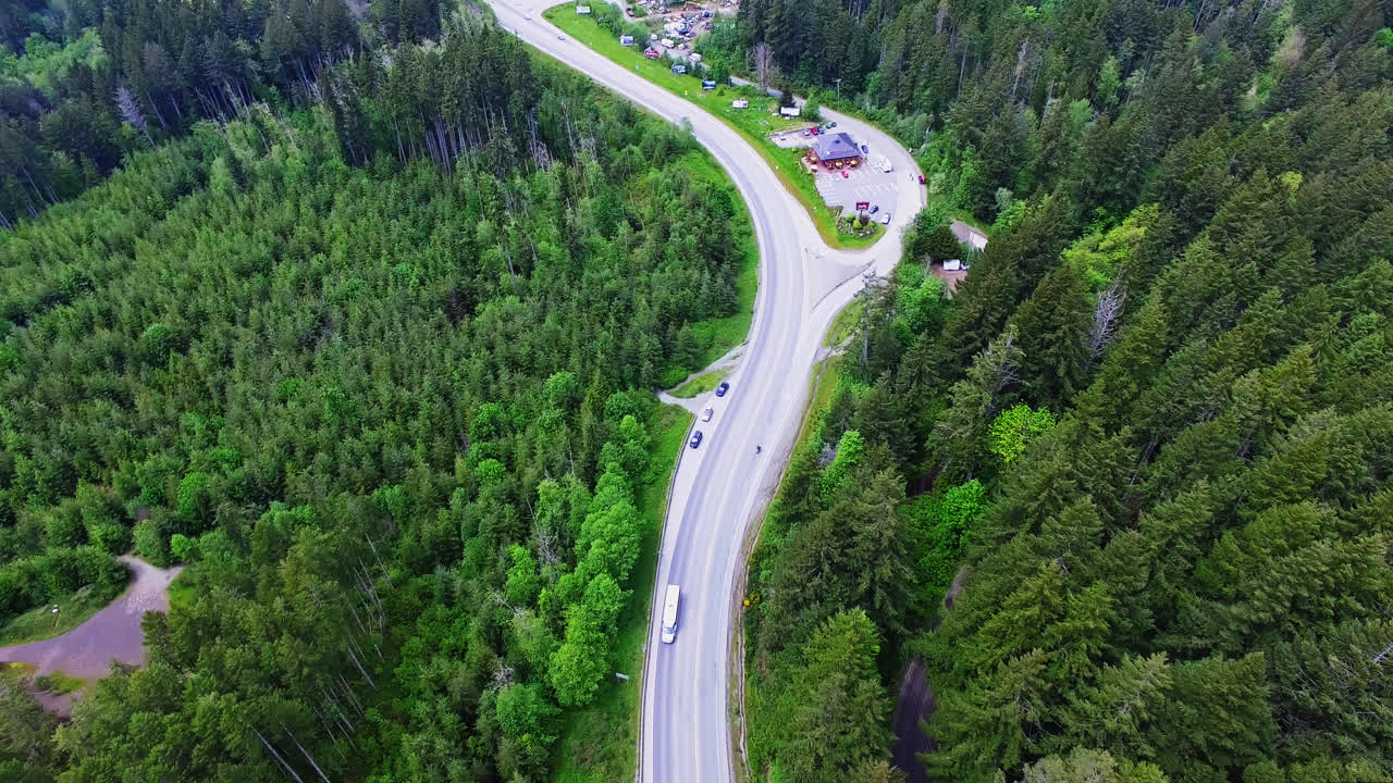 vehículos que conducen a lo largo de un camino rural curvo a través del bosque en la región de port alberni, columbia británica, canadá, vista aérea