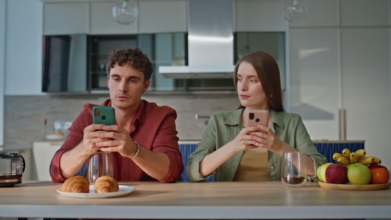 Ignoring spouses looking smartphones at home breakfast closeup. Two young people