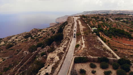 Turistas-Aventureros-Montando-Vehículos-Todo-Terreno-A-Lo-Largo-De-La-Carretera-Costera,-Impresionante-Paisaje-De-Gozo