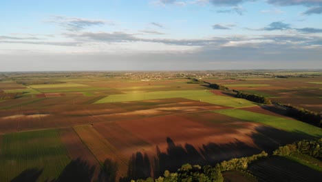 flying above a central european town's outskirts, landscape with long shadows in the sunset - drone shot, panning