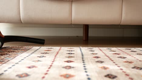 person vacuuming underneath a couch