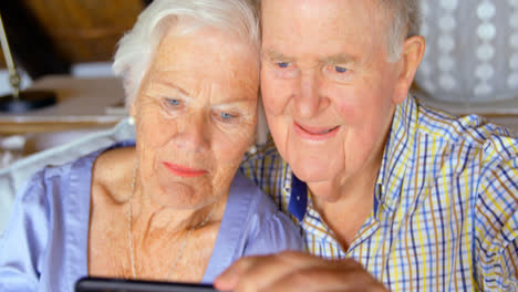 Front-view-of-old-Caucasian-senior-couple-taking-selfie-with-mobile-phone-at-comfortable-home-4k