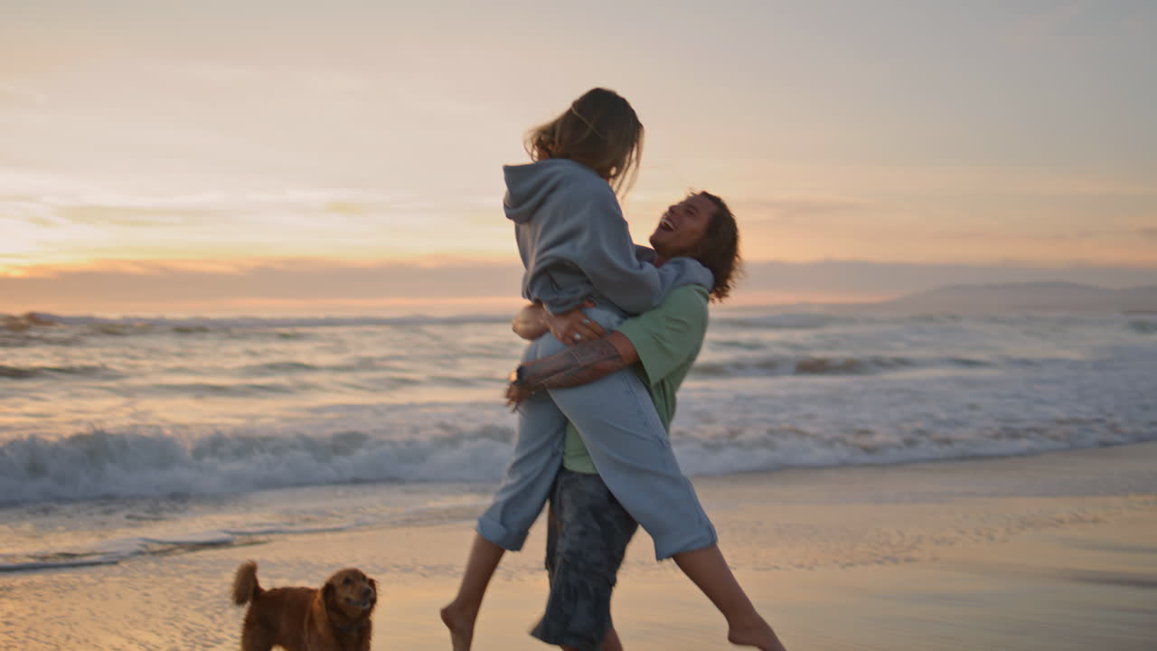 Couple Plays on the Beach at Sunset with Dog