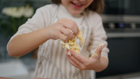 niño riendo haciendo masa en casa retrato. niña sonriente jugando con pasteles
