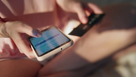 hands making online shopping holding smartphone closeup. girl insert debit card