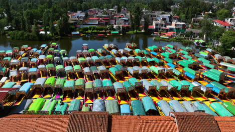 aerial tracking shot of trajinera boats docked at the xochimilco lake, in mexico