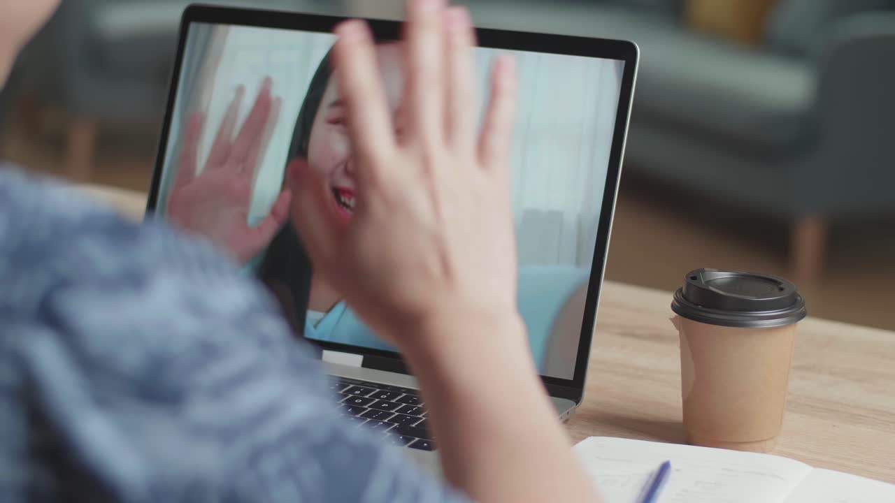 Man Waving Hand During Video Call With Asian Woman On Laptop Computer , Video In 4K