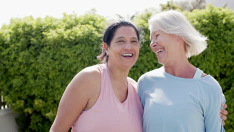 Dos-Mujeres-Mayores-Felices-Y-Diversas-Abrazándose-Y-Sonriendo-En-Un-Jardín-Soleado,-En-Cámara-Lenta