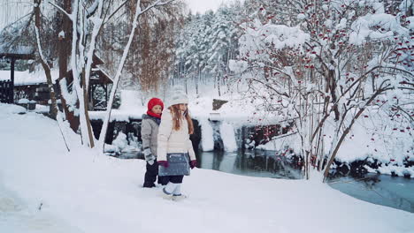 beautiful view of natural winter background and children standing near the river. little kids are looking at river in winter in the forest.