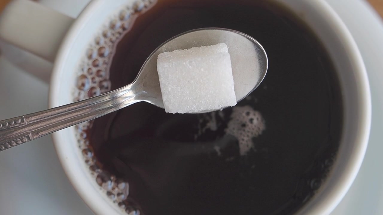 Zuccherino che cade in una tazza di caffè nero