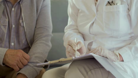 Close-up-shot-of-doctor-in-medical-gloves-writing-patients-notes