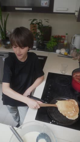 boy cooking pancakes in a kitchen
