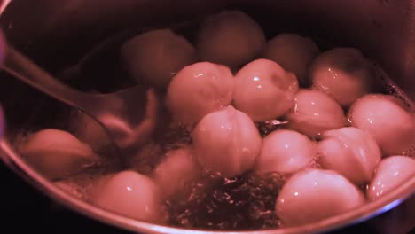 primer plano: cuchara agita la olla hirviendo en la estufa cocinando dumplings pelmeni