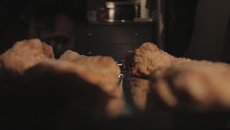 placing a tray of fried chicken inside the oven for baking - close up shot