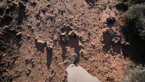 la cámara mira directamente al suelo mientras un hombre con botas de montaña camina por el suroeste americano