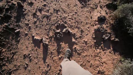 camera looks straight down at the ground while a male in hiking boots walks in the american southwest