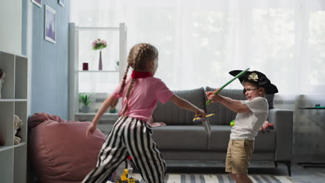 toddler and preschooler girl play with toy swords at home