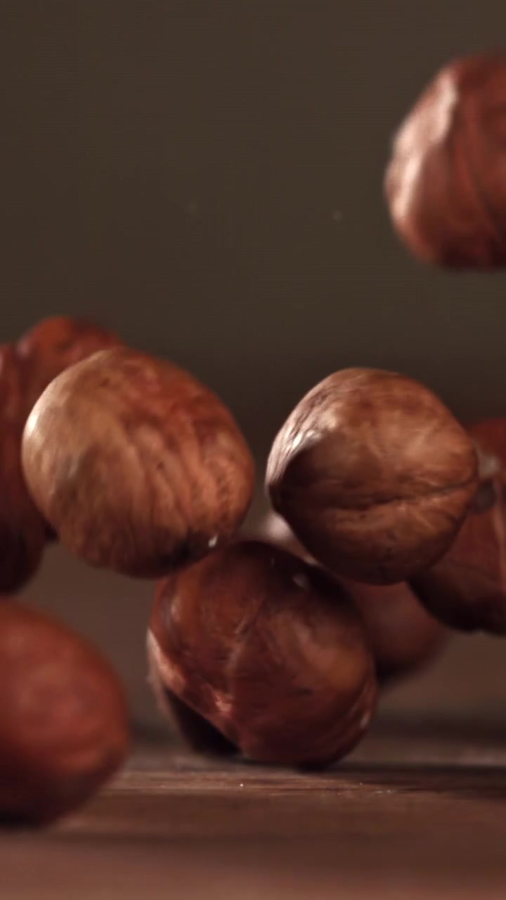 Nocciole che cadono al rallentatore su una superficie di legno