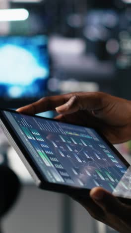 vertical video close up of data center engineer using tablet to review code