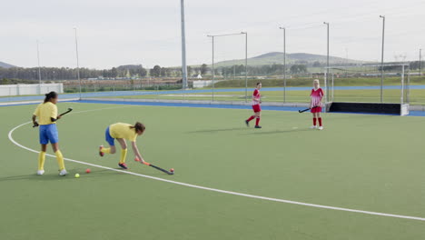 female hockey players competing intensely on outdoor field, focusing on teamwork