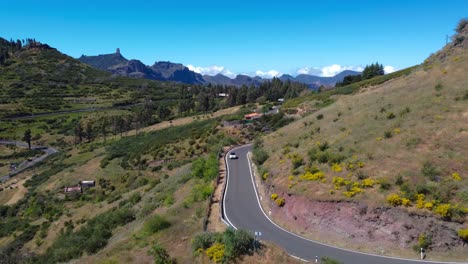 fotografía aérea de un avión no tripulado siguiendo a un coche que conduce por una hermosa carretera panorámica - gran canaria, españa
