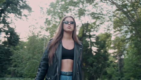 joven modelo quitándose el sombrero y caminando en el jardín