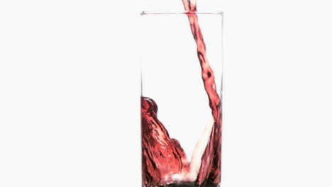 un goteo delgado rojo en un movimiento súper lento que fluye en un vaso