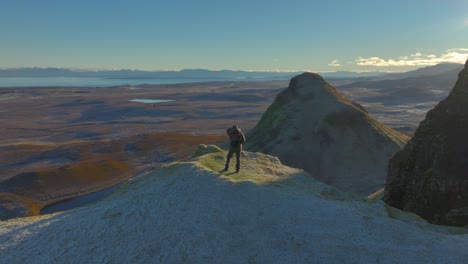 mountain walker standing on frosty cliff edge with far view to mountainous winter horizon at dawn