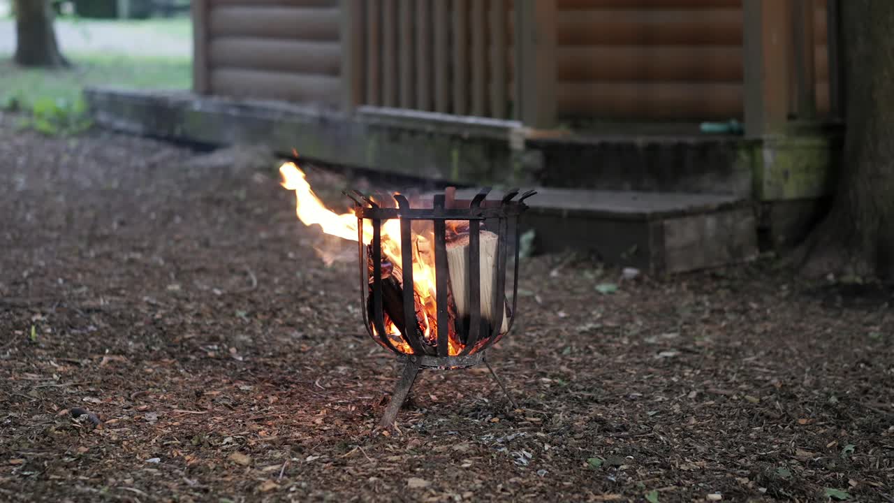 Fire pit with burning logs in a forest setting, medium parallax slider shot, daytime.