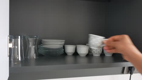 arranging dishes in a kitchen cabinet