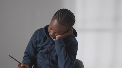 studio shot of boy at table concentrating on writing in school book