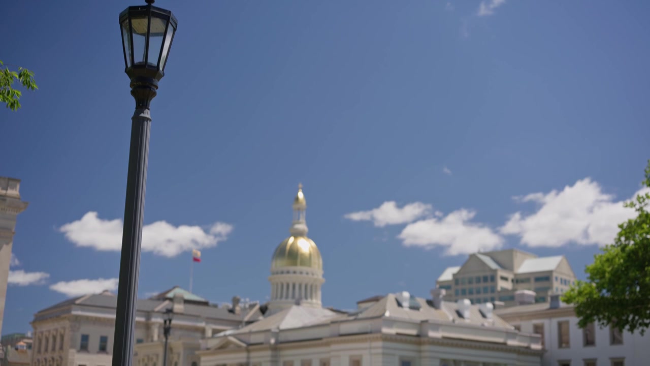 Vista cinematográfica em inclinação ascendente do edifício do Capitólio da Casa do Estado de Nova Jersey, emoldurado por um poste de luz histórico no centro de Trenton, Nova Jersey, em um dia claro