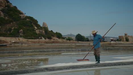man harvesting salt in a salt field