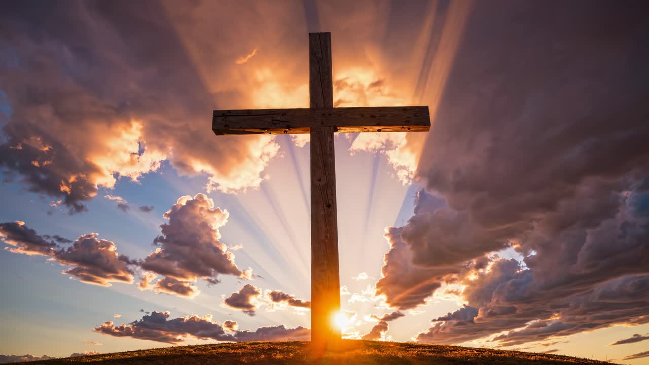 Dramatic video concept of a wooden cross silhouetted against a sunset sky