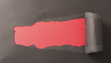 ripped black paper revealing copy space on red background