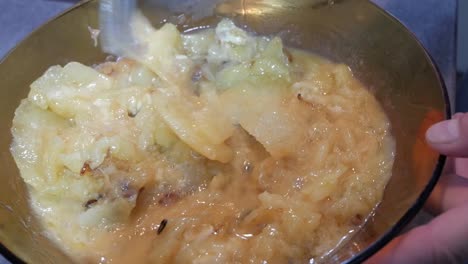 spanish tortilla, potato omelette, ingredients being mixed with fork inside a large glass bowl