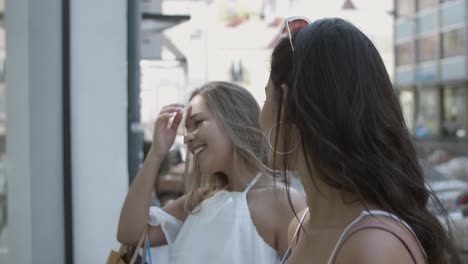 attractive young women talking on the street and watching shop window