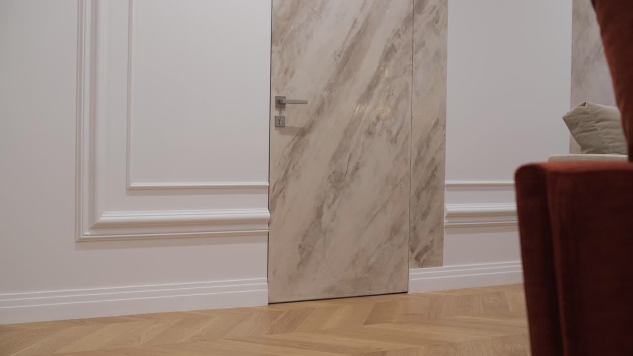 puerta de mármol en un interior de lujo con elegante moldura blanca y una vista parcial de una silla de tela, que combina elementos de diseño clásico y moderno