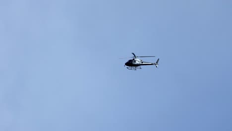 a helicopter flies steadily across a clear blue sky, captured in smooth motion with consistent lighting and serene atmosphere