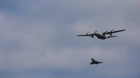 airplane of the type airbus a400m and the fighter aircraft types eurofighter fly through the air with clouds in the background. taken at the air show called airpower.