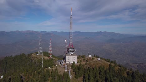 Cumbre-De-Heniu,-Rumania---Telecomunicaciones-En-El-Exuberante-Pico-De-La-Montaña-Con-Hermosas-Montañas-En-El-Fondo---Tiro-Panorámico-De-Drones