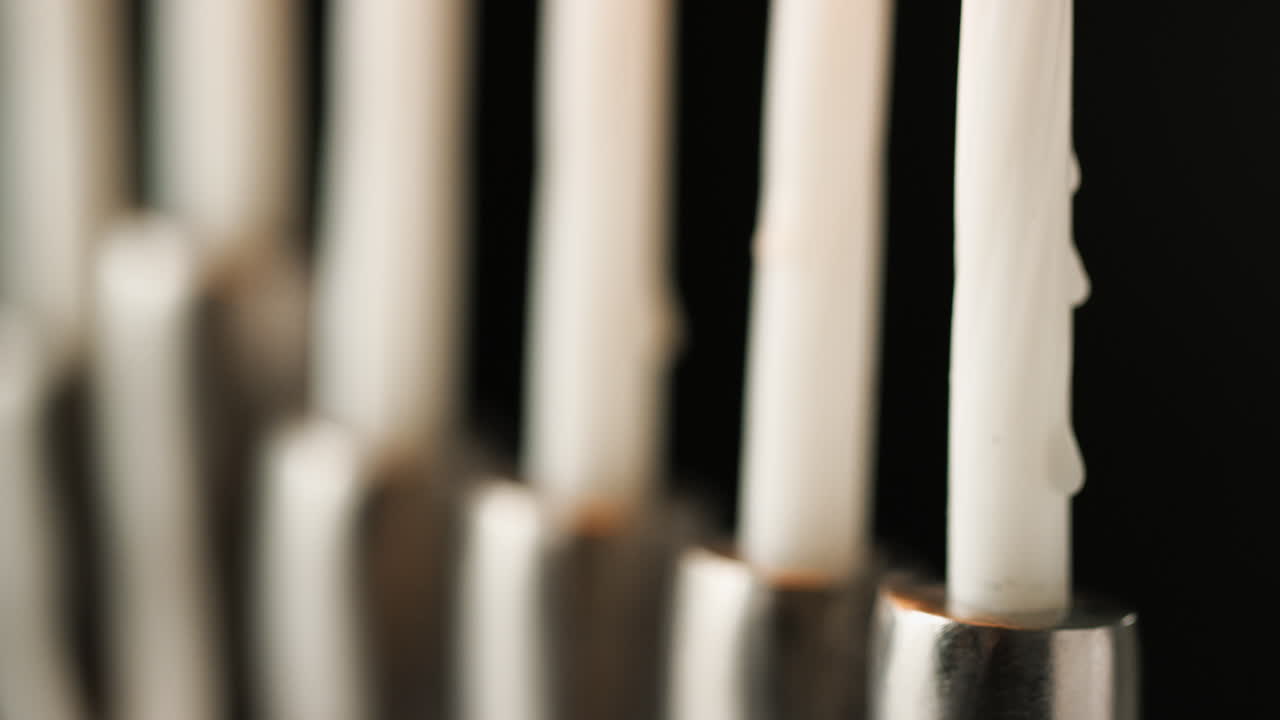 de cerca, poca profundidad de campo tiro de inclinación de la menorá de plata en ángulo, con velas blancas encendidas, detalle