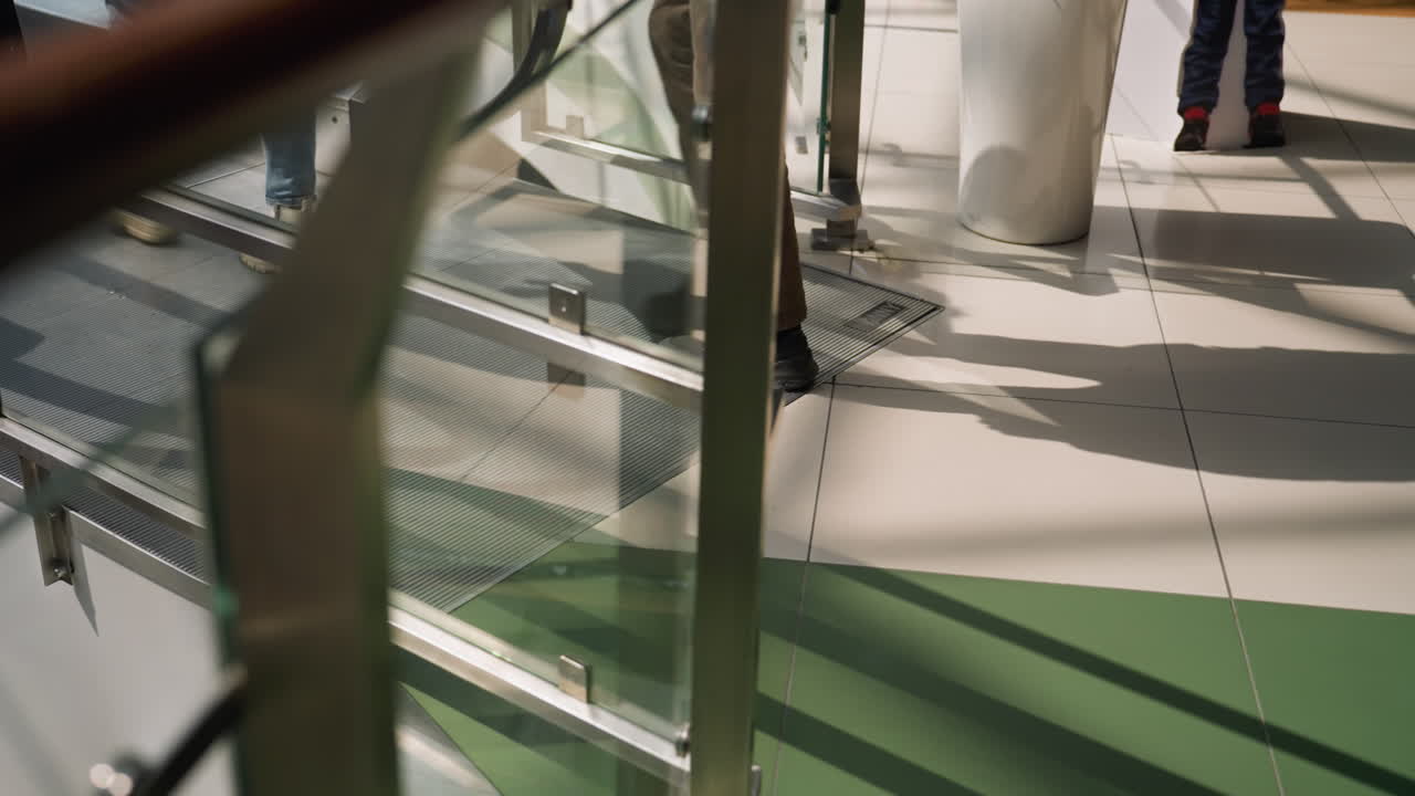 una escena dinámica que captura a la gente moviéndose en un centro comercial, centrándose en la mitad inferior de sus cuerpos, mostrando piernas en movimiento y partes de la estructura interior del centro comercial