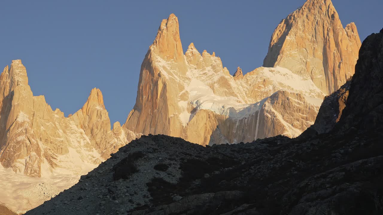 Luce dorata del mattino illumina il Monte Poincenot in Patagonia, evidenziando vette aspre e neve