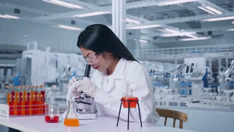 vista lateral de una mujer científica mirando a través de un microscopio en la mesa con un tubo de ensayo luego sonriendo y diciendo wow en el laboratorio, trabajando en el laboratorio analizando muestras bajo el microscopio