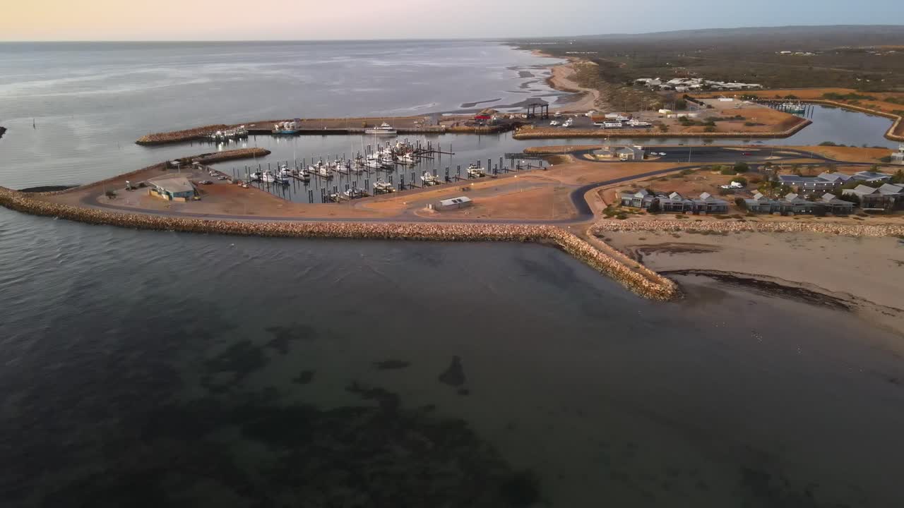 drone aéreo panorámico lentamente sobre el océano durante la puesta de sol sobre el puerto de exmouth