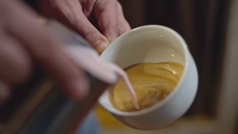 Closeup-Hands-Of-Barista-Pouring-Strawberry-Steamed-Milk-From-Stainless-Steel-Pitcher-Into-Cup-Of-Espresso-In-Shape-Of-Heart-To-Make-Latte-Art,-Slow-Motion-Shot